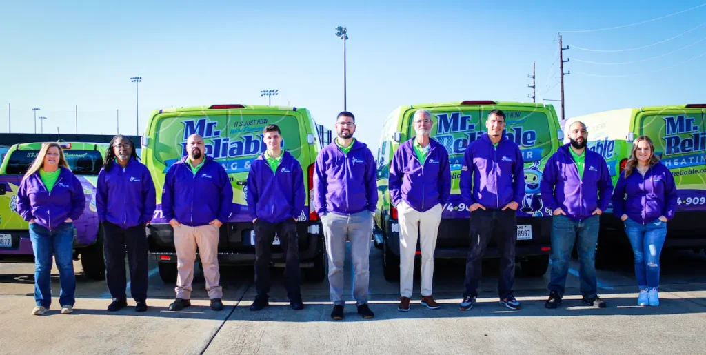 Mr. Reliable staff standing in front of two company trucks